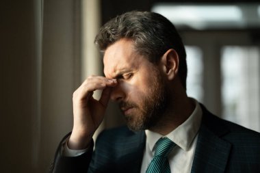 Yorgun adamın korkunç bir baş ağrısı var. Bitkin, sağlıksız hisseden, baş ağrısı hastalığına üzülen bir adam. Stresli orta yaşlı adamın başı ağrıyor. Migren ve baş ağrısı konsepti
