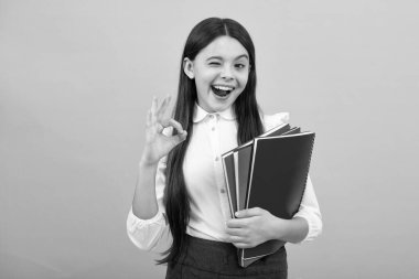 Heyecanlı bir yüz. Kitapları olan liseli bir kız. Öğrenci kız. Şaşırtıcı bir ifade, neşeli ve mutlu.