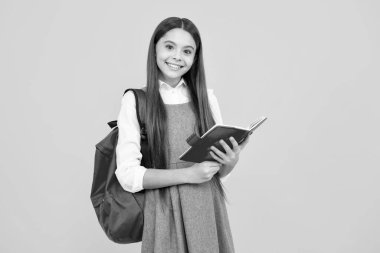 Liseli kızın elinde sarı izole edilmiş stüdyo geçmişi ile ilgili defter ve kitap var. Okul ve eğitim kavramı. Okul üniformalı ergen kız.