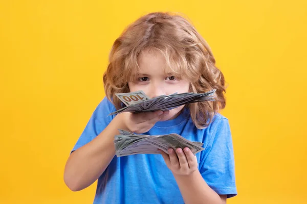 Money win, big luck. Kid with lots of money dollar banknotes isolated over yellow studio background