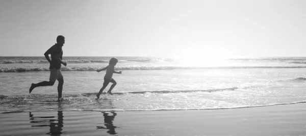 父亲和儿子的轮廓在夏天的海滩上跑来跑去 横幅招贴画与复制空间 爸爸带着小孩在海里或海里周末家庭日 — 图库照片