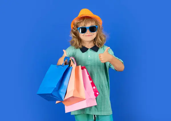 stock image Portrait of kid with shopping bag on blue isolated background. Portrait of a kid with shopping bags. Cyber monday, black friday. Small child enjoy shopping