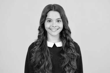 Portrait of cute positive little girl isolated on yellow background. Attractive caucasian child smiling and looking at camera