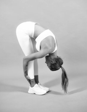 Sporda gülümseyen genç bir kadının tüm vücudu esneyerek gri arka planda izole olur. Sağlıklı, güzel sporcu kadın.