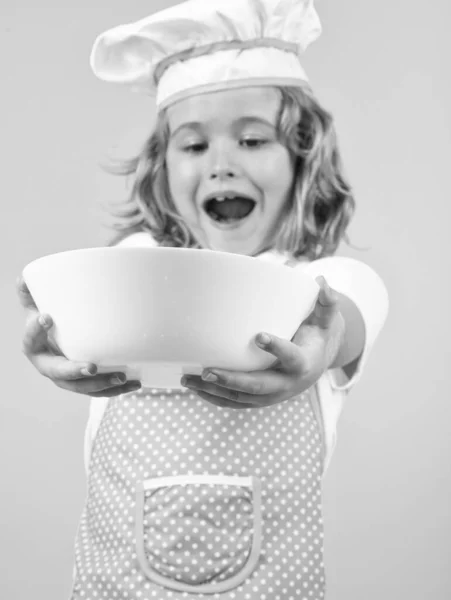 Funny kid chef cook with kitchen plate, studio portrait. Chef kid preparing healthy food. Portrait of child with chef hats