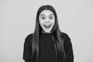 Heyecanlı çocuk suratı. Şaşırtıcı bir ifade, neşeli ve mutlu. Heyecanlı genç kız heyecanla ağzını açıyor, sarı stüdyo arka planında büyük satış ya da tanıtım olduğuna inanıyor.