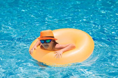 Yüzme havuzunda su sıçratan çocuk. Aktif sağlıklı yaşam tarzı, çocukla yaz tatilinde yüzme sporu aktivitesi. Çocuk su oyuncakları