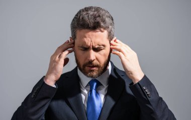 Takım elbiseli stresli iş adamının başı ağrıyor. Yorgun iş adamı fazla mesai yapıyor ve başı ağrıyor. Çok çalışan adam baş ağrısından muzdariptir. Aşırı çalışma, teslim tarihi, iş yerinde zor migren.