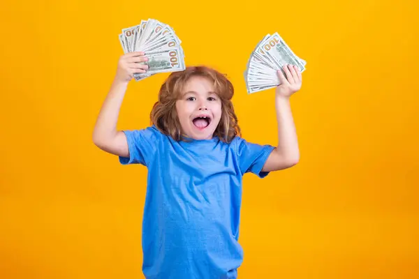 Money win, big luck. Child with lots of money dollar banknotes isolated over yellow studio background