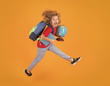 Shool kid jump with school bag and globe. Full length body of little school kid jumping having fun isolated yellow color background. Crazy school boy jump clipart