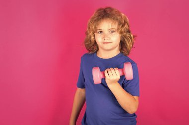 Sportif çocuklar, stüdyo portresi. Dambıl kaldıran çocuk. Dambılı şirin çocuk eğitimi. Çocuk fitness. Çocuk, dambıllarla egzersiz yapıyor. Sağlıklı çocuklar