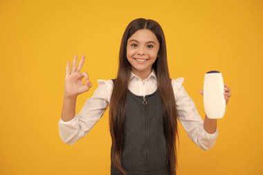 Şişe şampuanı ya da duş jeli olan ergen bir kız. Çocukların saç bakımı. Saç makyaj ürünü, şampuan şişesi.