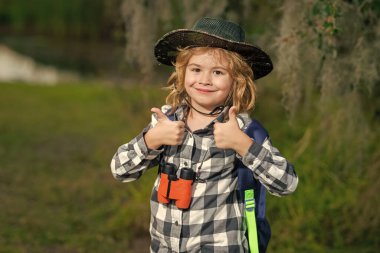 Dürbünlü çocuk dışarıda geziyor. Yaz günü sırt çantalı bir gezgin. Vahşi hayatı keşfeden küçük bir çocuğun portresi. Yürüyüş ve macera konsepti