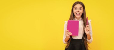 Happy child genius hold school book pointing pen up yellow background, idea. Banner of schoolgirl student. School child pupil portrait with copy space