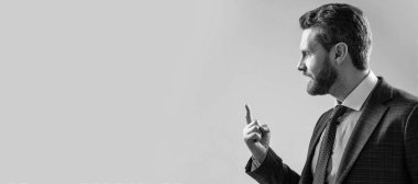 Takım elbiseli profesyonel adam arka plandaki gri fotokopi alanını işaret etmeye devam et. İnsan yüzü portresi, fotokopi alanı olan pankart. Takım elbiseli bir iş adamı, izole stüdyo geçmişi var.