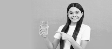 Mutlu çocuk susuz kalmamak için bir bardak su içer ve günlük su dengesini sağlar. Bir bardak suyu olan kız çocuğu afişi, fotokopi alanı olan stüdyo resmi