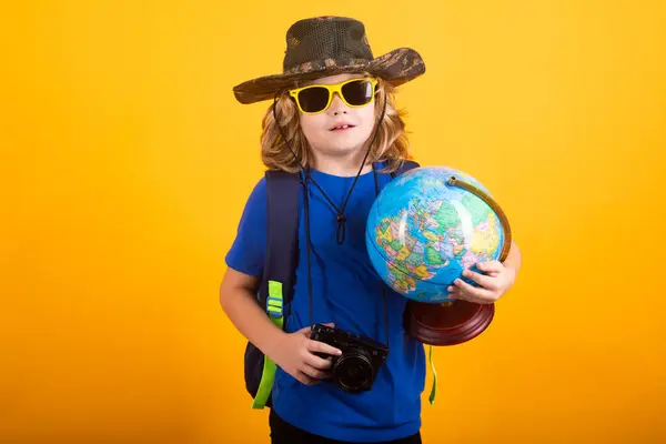 Studio portrait on a yellow background. Kid with earth planet model hiking at nature. Little explorer. Child tourist on yellow background