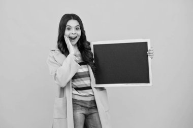 School sales board. Cheerful teenage girl kid hold blackboard chalkboard with copy space. Amazed teenager. Excited teen girl