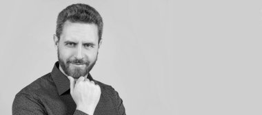 Yakışıklı, orta yaşlı, sakallı, şık saç kesimi olan, günlük gömlekli, berber dükkanında poz veren biri. İnsan yüzü portresi, kopyalama alanı olan pankart