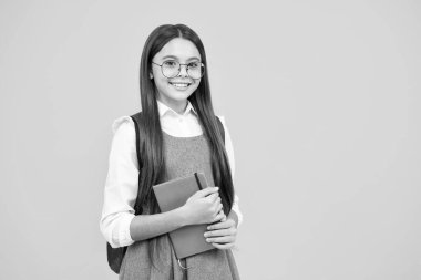 Kopya kitabı olan liseli kız izole edilmiş arka planda poz veriyor. Edebiyat dersi, ilkokul. Entelektüel çocuk okuyucu