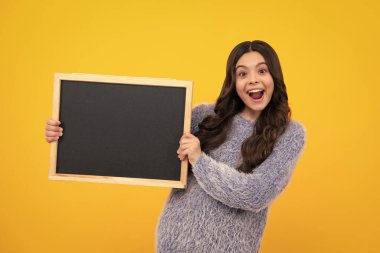 School sales board. Cheerful teenage girl kid hold blackboard chalkboard with copy space. Amazed teenager. Excited teen girl