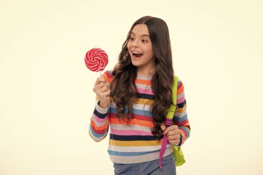 Hippi ergen kız lolipopu yalıyor. Şeker, şeker ve şekerleme. Çocuk lolipop şekeri yiyor. Heyecanlı bir yüz, neşeli genç bir kız.