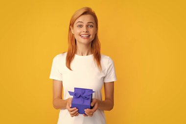 Şu anki kutusuyla çekici bir kadın gri arka planda şaşırmış yüz ifadesiyle poz veriyor. Kız elinde kurdeleyle süslenmiş bir hediye tutuyor. Sevgililer günü, doğum günü, mutlu yıllar hediye insanlar konsepti