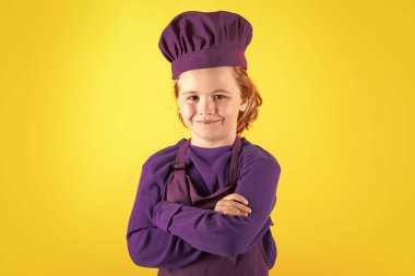 Aşçı çocuk, stüdyo resmi. Çocuklar yemek yapıyor. Önlüklü ve aşçı şapkalı çocuk.