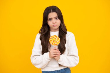 Sarı izole edilmiş arka planda lolipopu olan komik çocuk. Tatlı çocukluk hayatı. Lezzetli karamel lolipopu olan genç kız, şekerci. Kızgın yüz, üzgün genç kız duyguları..