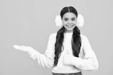 Modern teenage girl 12, 13, 14 year old wearing sweater and knitted hat on isolated yellow background. Happy face, positive and smiling emotions of teenager girl