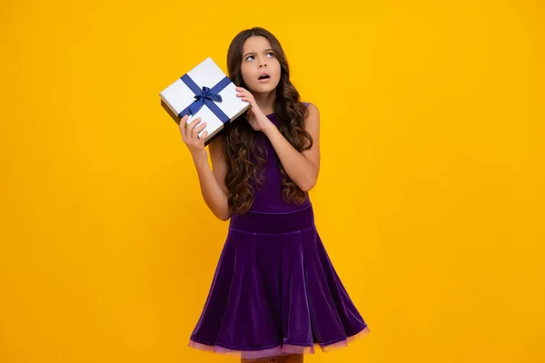 Child with gift present box on isolated background. Presents for birthday, Valentines day, New Year or Christmas. Angry teenager girl, upset and unhappy negative emotion