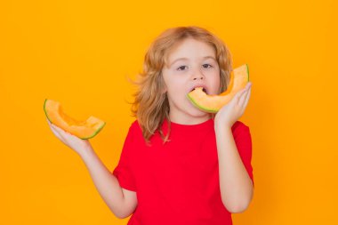 Çocuklar için vitamin ve sağlıklı meyveler. Çocuk stüdyoda kavun yiyor. Kavun meyvesi. Stüdyo portresi. Karpuz sarılı şirin bir çocuk.