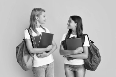 Mother and daughter, happy family preparing for school. Little girl with mother learning, preparing to school on isolated yellow studio background