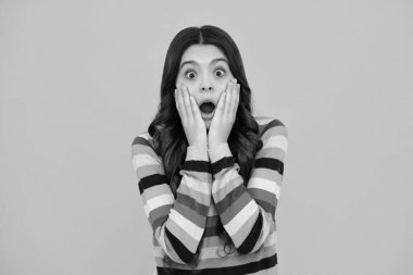 Shocked amazed face, surprised emotions of young teenager girl. Cute young teenager girl against a isolated background. Studio portrait of pretty beautiful child