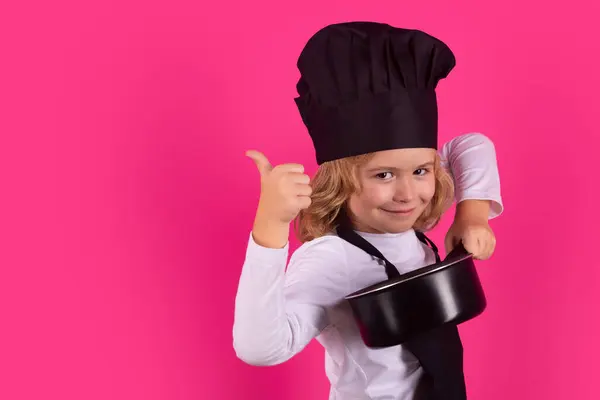 Child chef cook with cooking pot. Child in cook uniform. Chef kid isolated on pink background. Cute child to be a chef. Child dressed as a chef hat