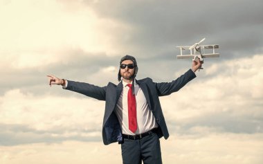 Takım elbiseli iş adamı ve pilot şapkalı uçak oyuncağı gökyüzünde. meydan okuma.