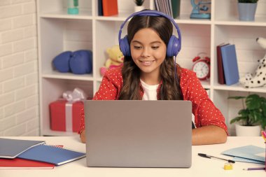 Genç bir liseli kız ders çalışırken dizüstü bilgisayar kullanıyor. Mutlu kız yüzü, pozitif ve gülümseyen duygular