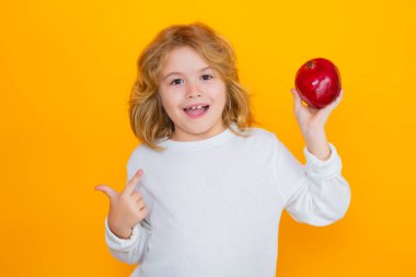 Çocuklar için vitamin ve sağlıklı meyveler. Çocuk stüdyoda kırmızı nar tutuyor. Nar meyvesi. Sarı arka planda izole edilmiş narlı şirin bir çocuğun stüdyo portresi.