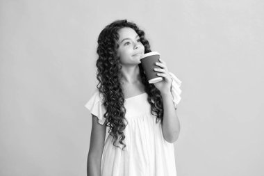 Bir fincan cappuccino kahvesi ya da çayı götüren genç kız. Sarı arka planda yemek fincanı olan çocuk, sabah içeceği. Mutlu ergen portresi. Gülümseyen kız