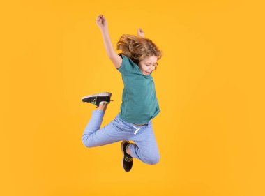 Full body of little child jump wear casual t-shirt and jeans isolated on yellow background