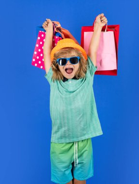 Fashion child on shopping. Portrait of a kid with shopping bags. Happy boy holding shopping bags. Studio portrait