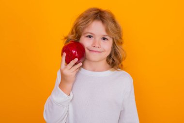 Çocuklar için sağlıklı meyveler. Çocuk stüdyoda kırmızı nar tutuyor. Nar meyvesi. Sarı arka planda izole edilmiş narlı şirin bir çocuğun stüdyo portresi.