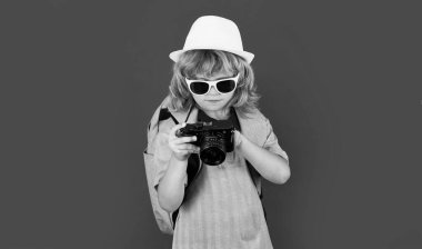 Kameralı çocuk gezgin fotoğrafçı stüdyoda fotoğraf çekiyor. Çocuk fotoğraf makinesi. Yaşam tarzı seyahat kavramı