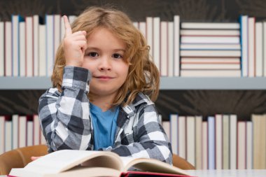 Child reading a book in a school library. School boy education concept