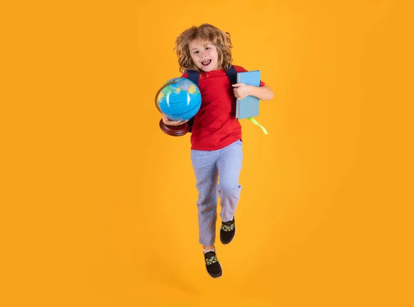 Back to school. Funny child school boy jumping on a yellow studio background
