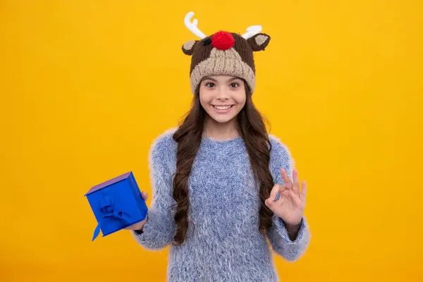 Teenager child in winter wear holding gift boxes celebrating happy New Year or Christmas. Winter kids holiday. Happy girl face, positive and smiling emotions
