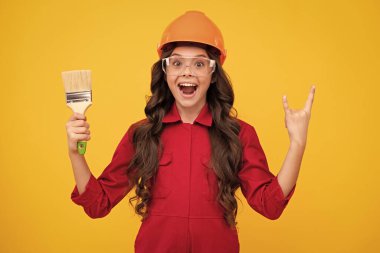 İnşaat alanında küçük miğfer ustası. Fırça aletli ya da boya silindirli genç kız ressam. Tamir işinde olan bir çocuk. Yenileme konsepti. Mutlu gülümseyen kız