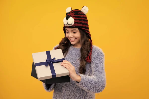 Happy teenager, positive and smiling emotions of teen girl. Funny kid girl in winter wear holding gift boxes celebrating happy New Year or Christmas. Winter holiday