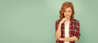 Mavi arka planda kareli gömlekli, kızıl saçlı, çapkın bir kadın. İzole edilmiş yüz portresi, kopyalama alanı oluşturulmuş pankart