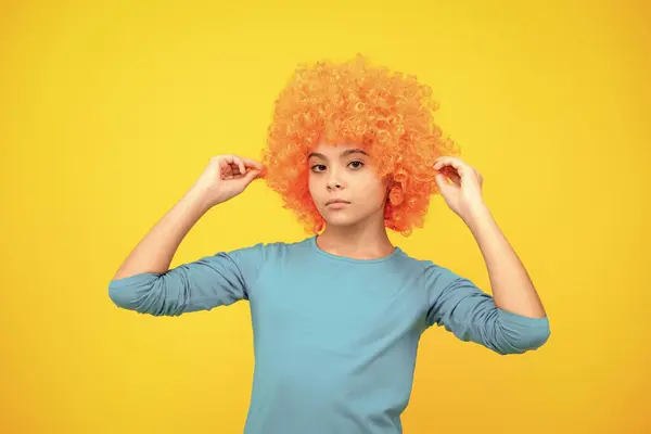 Beautiful teenage girl in wig isolated on yellow. Funny clown wig